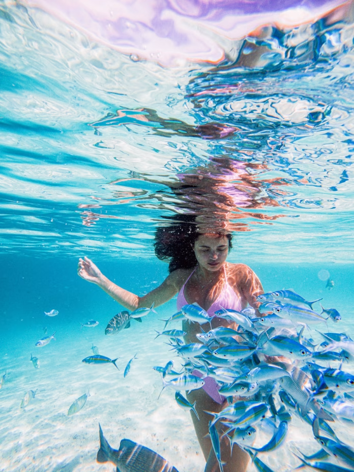 Young woman snorkeling in crystal-clear Maldives waters, surrounded by colorful coral and tropical fish – top-rated activity for first-time visitors